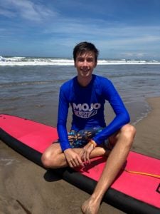 Image of Alex Heintze sitting on a pink surfboard